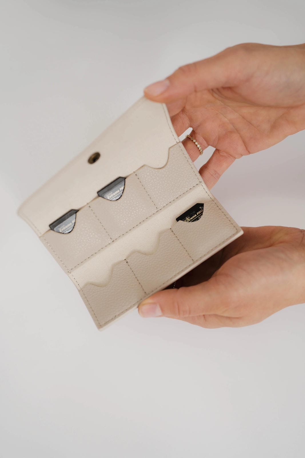 Beige wallet with cat face designs held by a hand on a light background