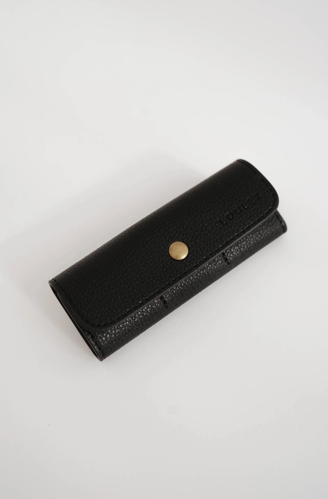 Black leather wallet with a gold button on a white background