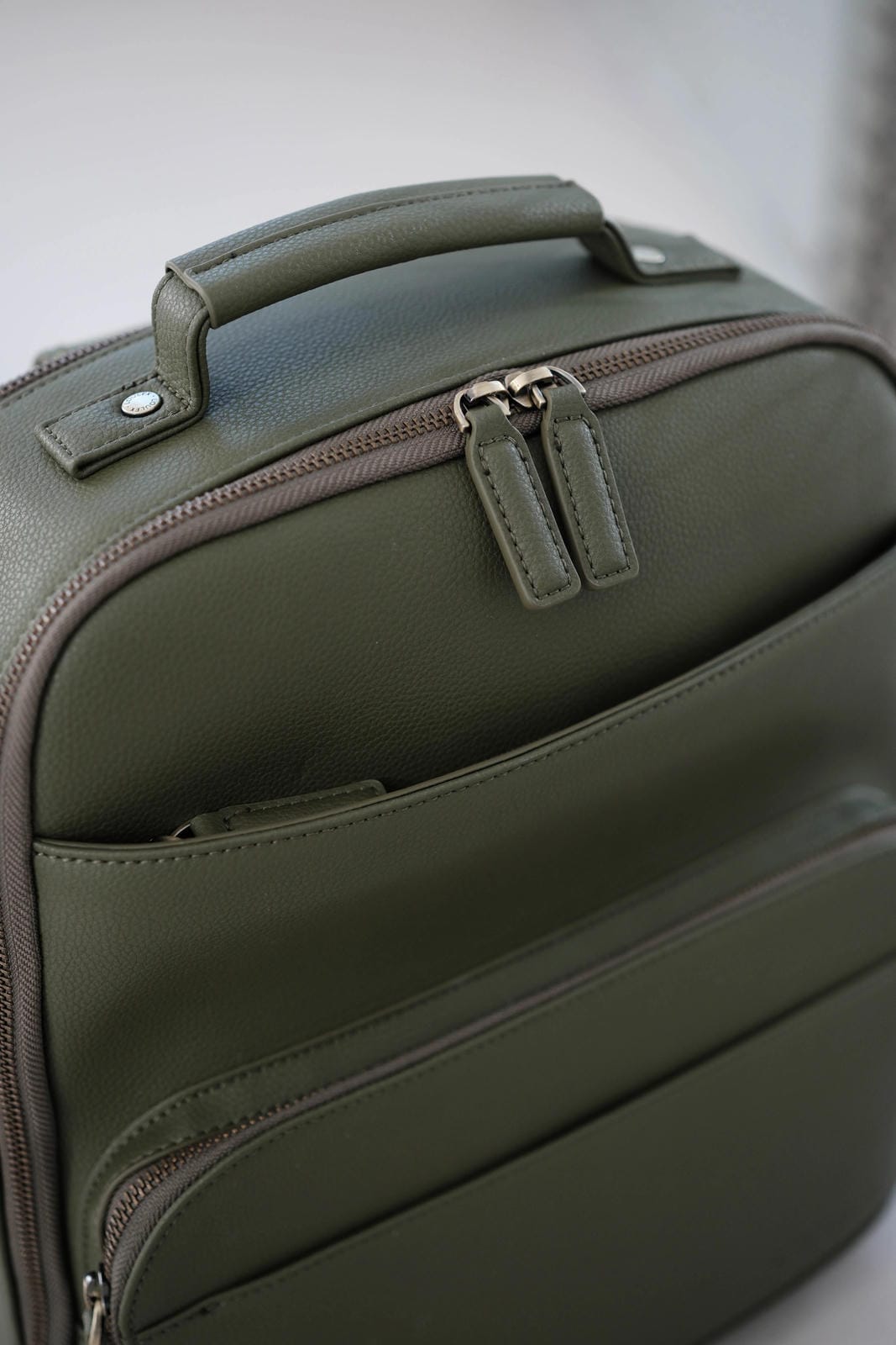 Green suitcase with zippers on a light gray background