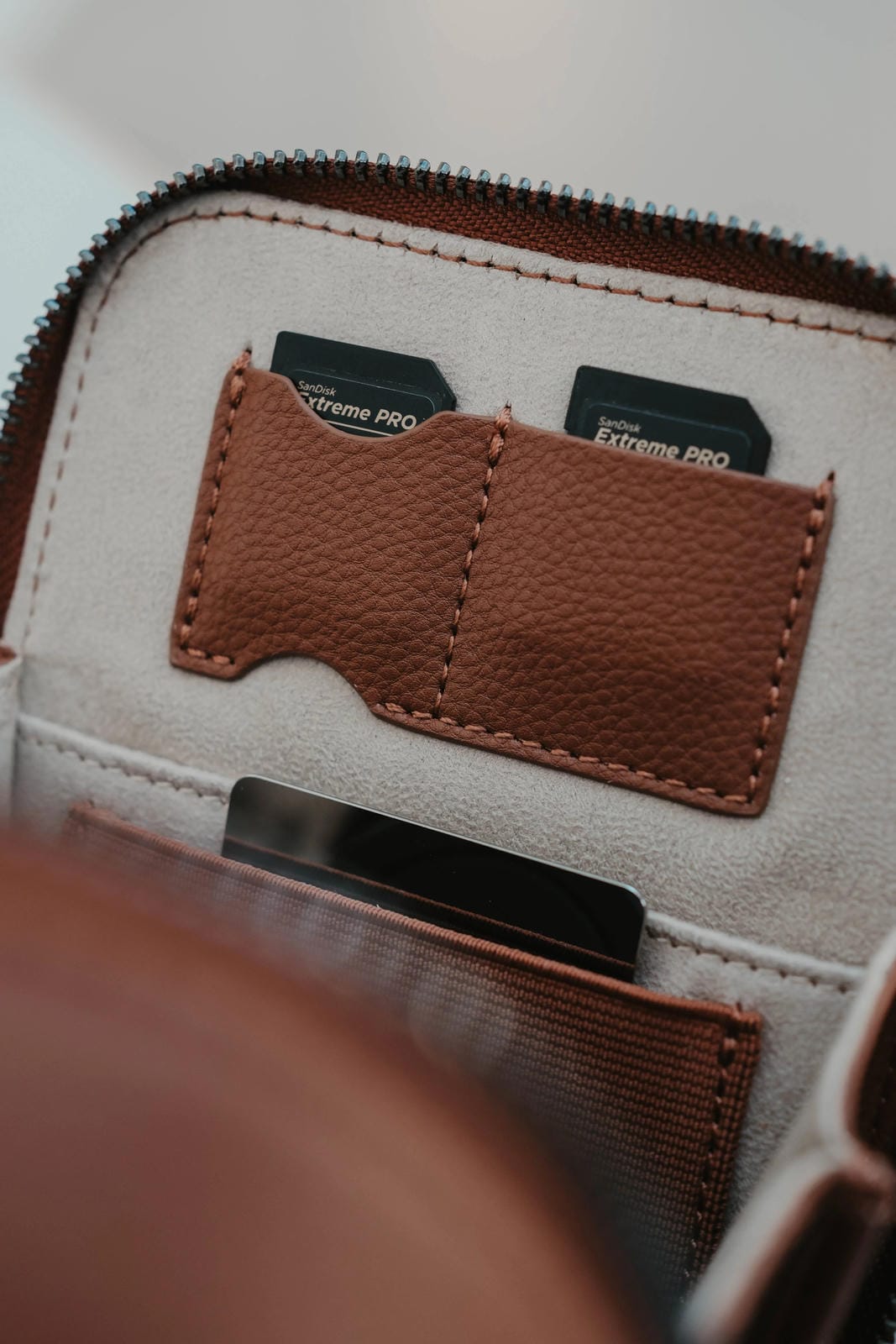 Close-up of a beige pouch with brown leather patch and Extreme Pro cards.