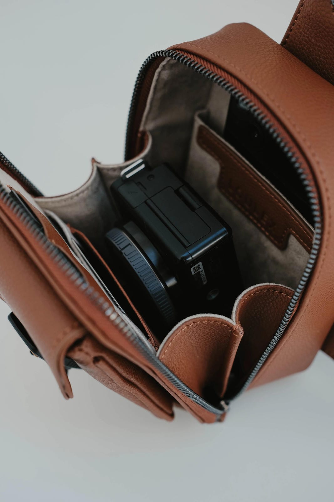 Brown leather bag with a black electronic device inside on a white background