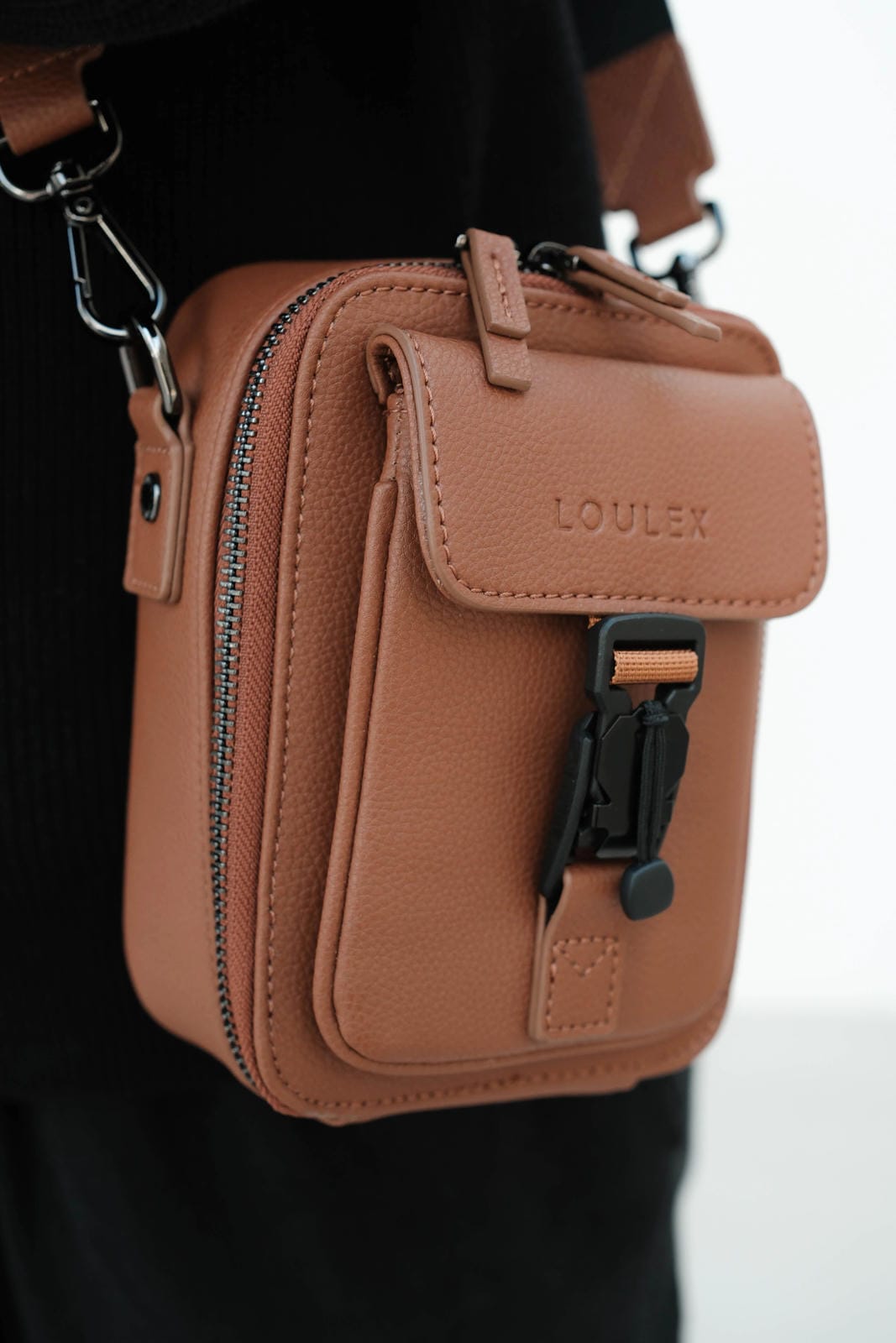 Brown leather bag with 'LOULEX' branding on a blurred background