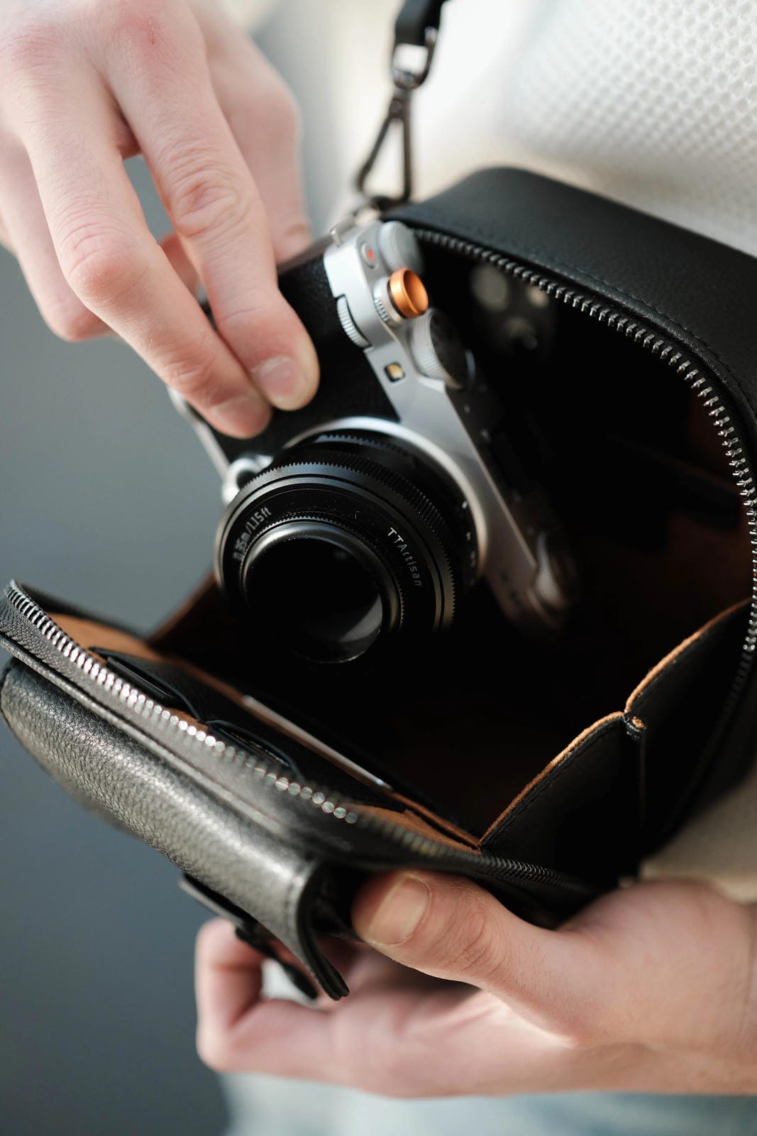 Person holding a camera in a leather case