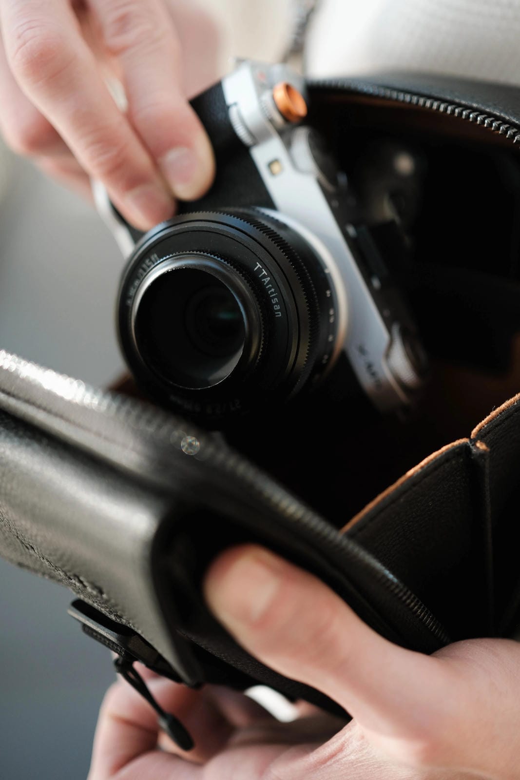 Person holding a camera and its case, with a blurred background