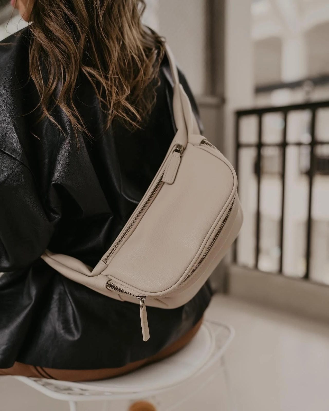 Person wearing a beige crossbody bag with a blurred background