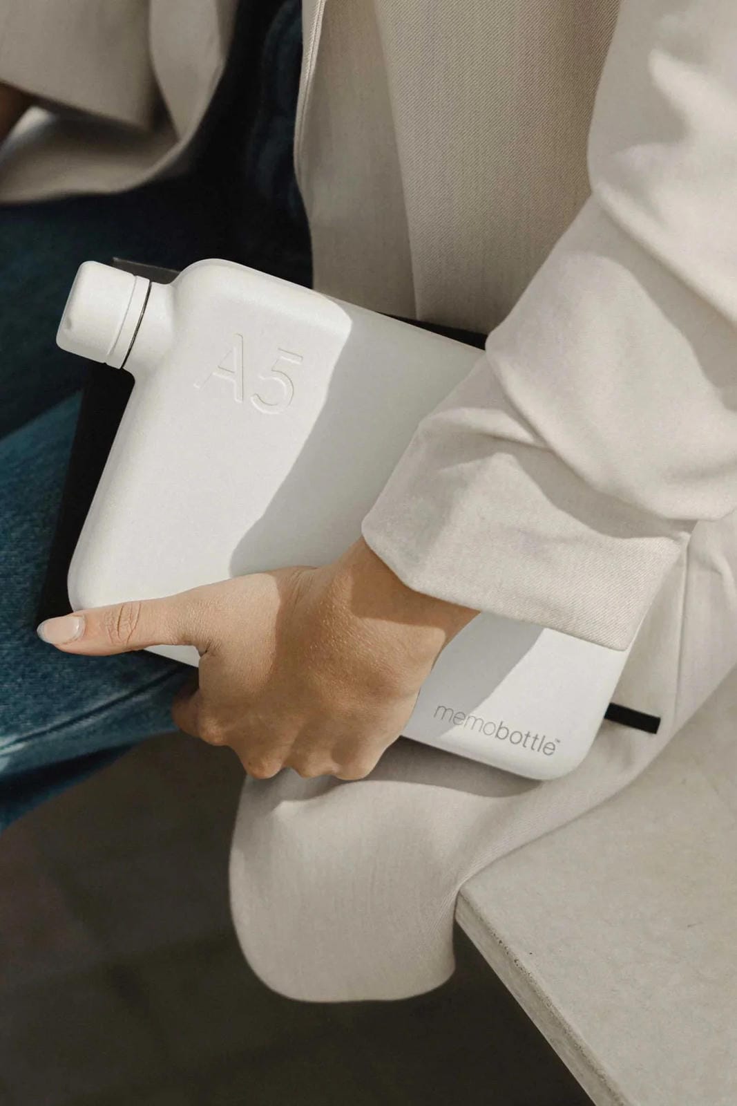 Person holding a white water bottle with a visible brand logo.