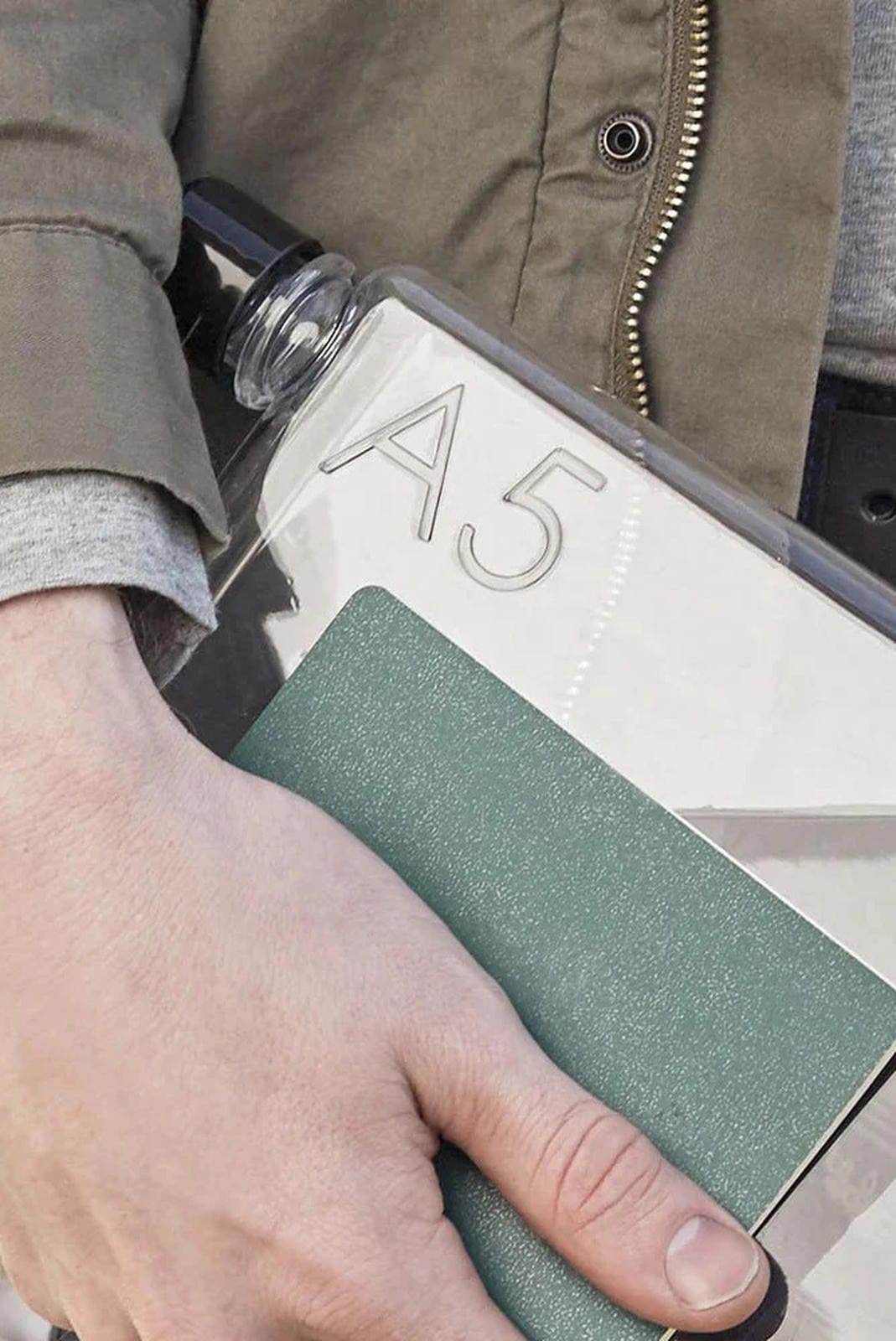 Hand holding a green notebook with 'A5' branding against a neutral background