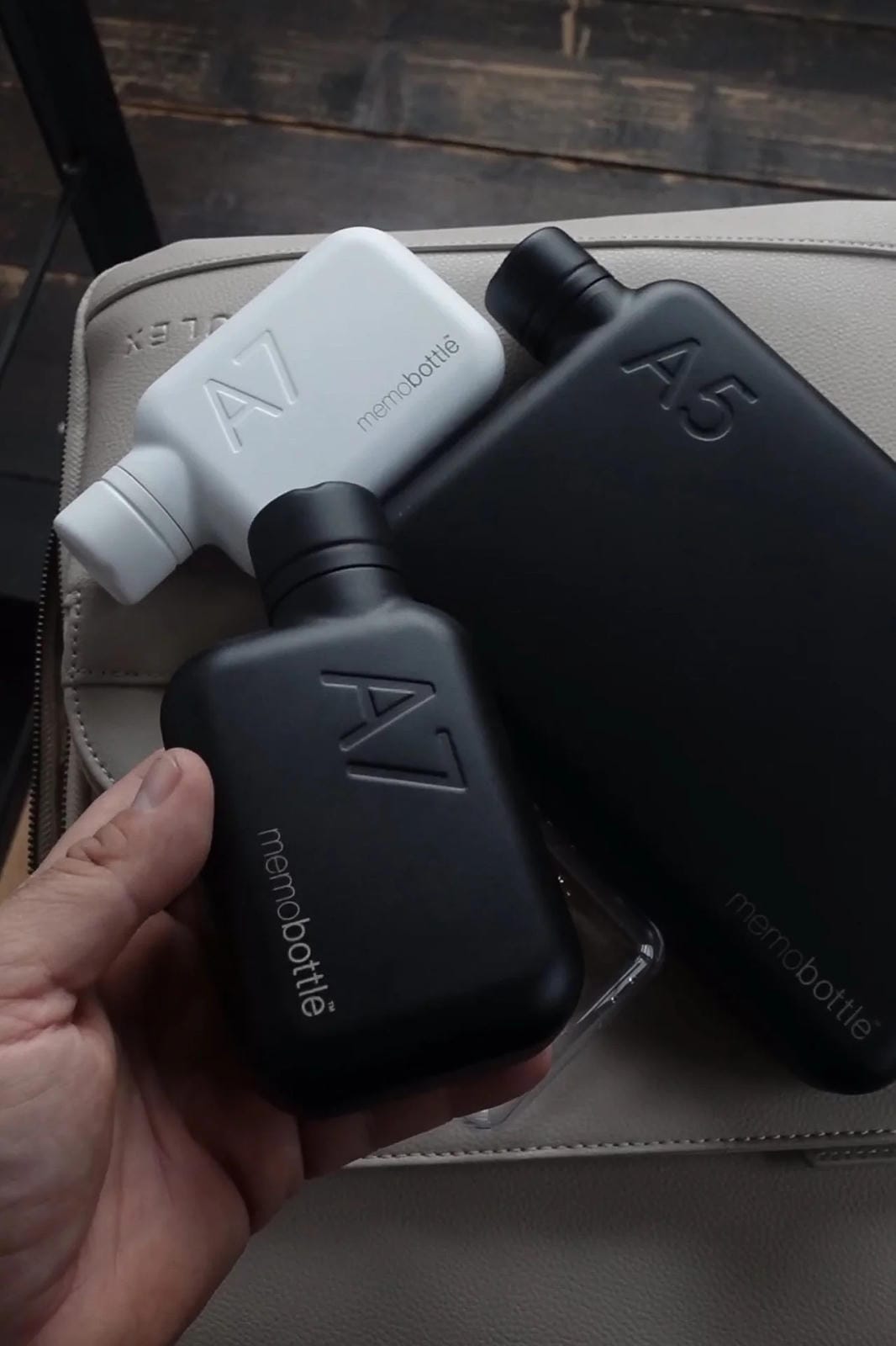 Black and white bottles with 'mercadotable' branding held by a hand on a wooden surface.