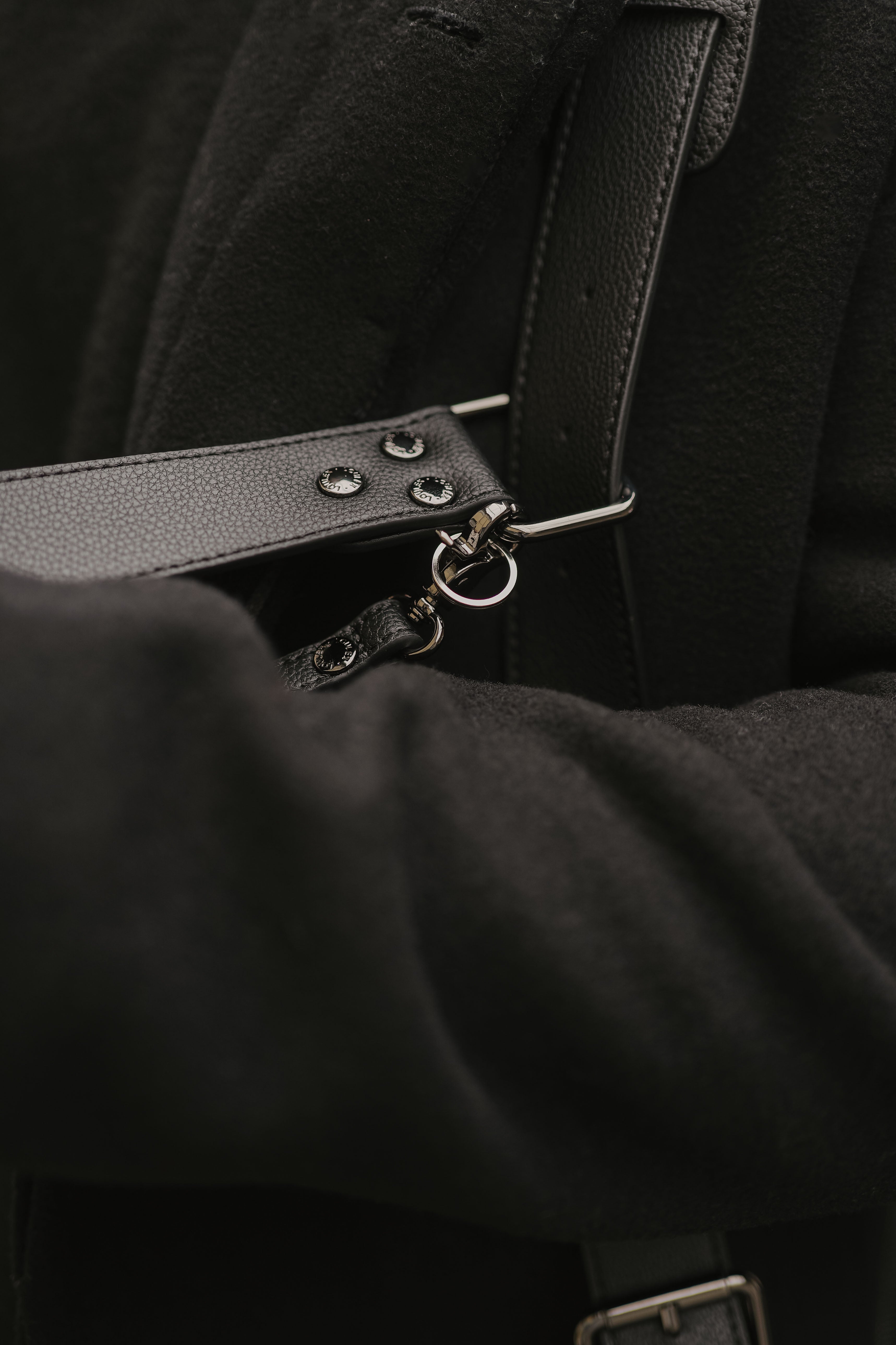 Close-up van een zwarte leren riem met metalen details op een donkere achtergrond