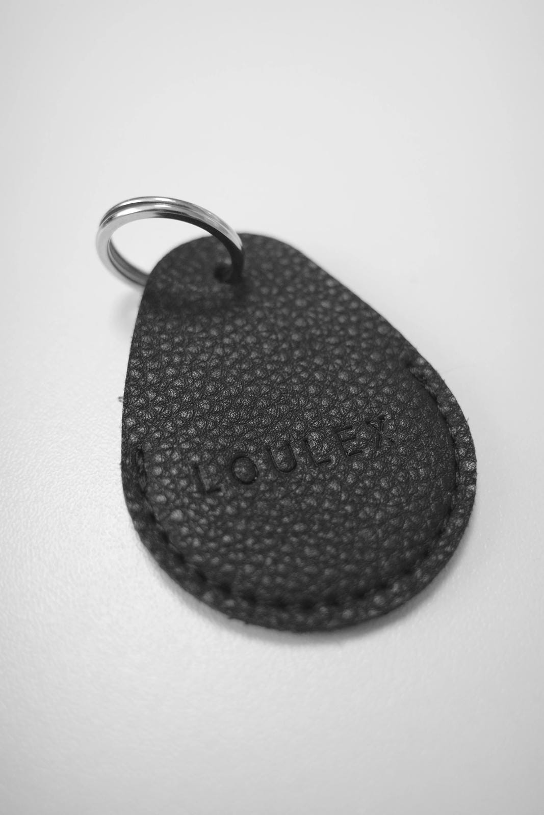 Black textured keychain with 'LOUCE' branding on a white background