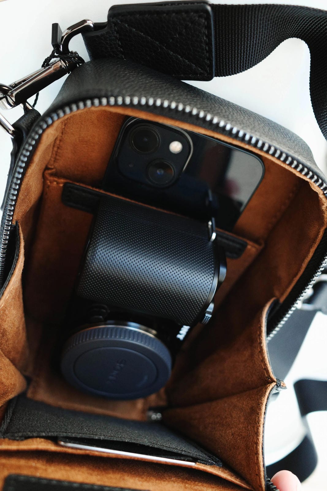 Brown leather bag with a camera inside, on a white background