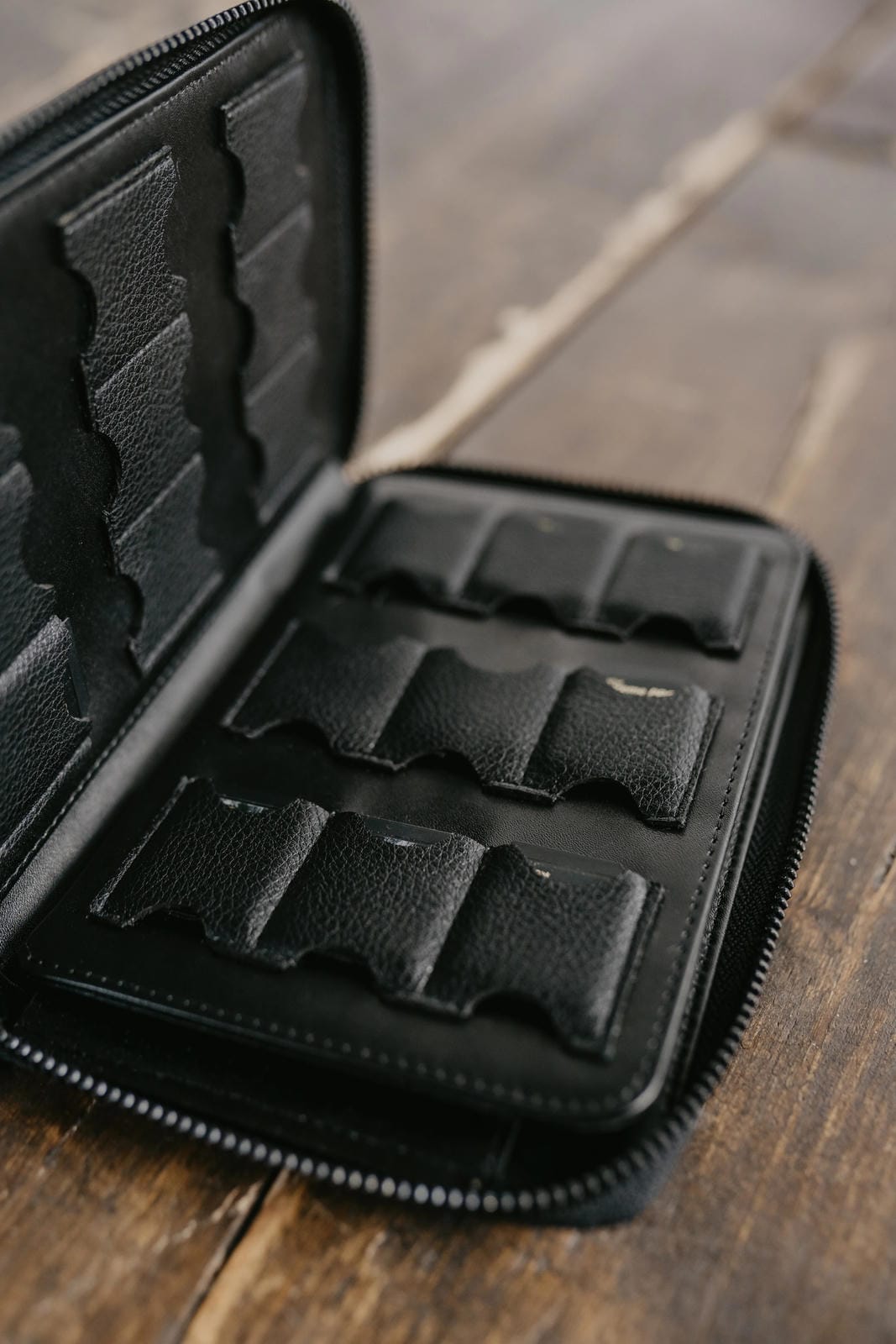 Black leather case with compartments on a wooden surface